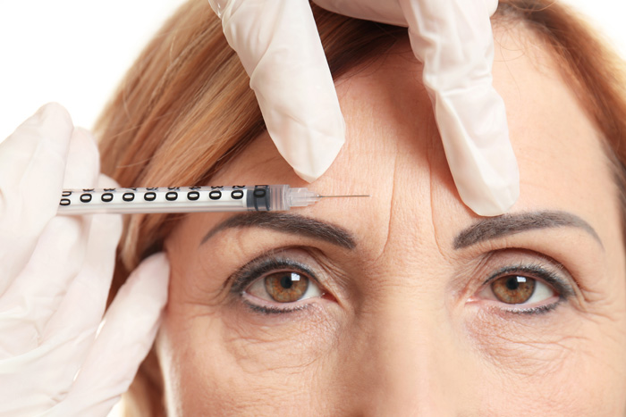 Woman whose brow has drooped receiving a Botox injection to lift the brow 